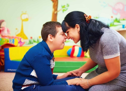 Mother presses her forehead against her son's forehead who has special needs