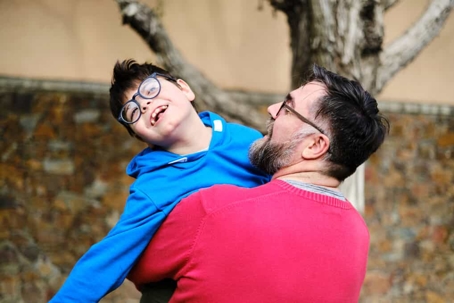 Father holds his young son with special needs in the air
