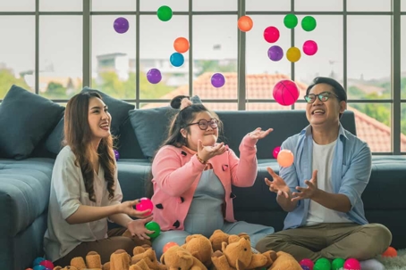 Girl with special needs plays with balls with her parents indoors