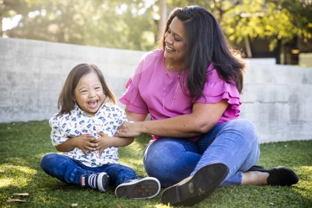 Mother plays in the grass with her young daughter with special needs