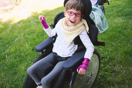 Young girl with special needs in a wheel chair smiles outside