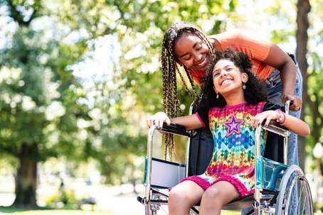 Young girl in wheelchair is pushed by her mother