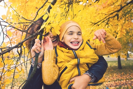 mother hugging and laughing with her son on a fall day
