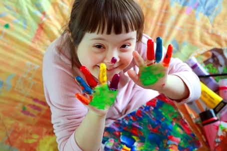 little girl with painted hands smiling