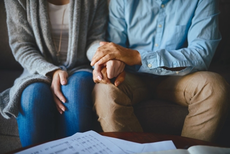 couple sitting on a couch, holding hands
